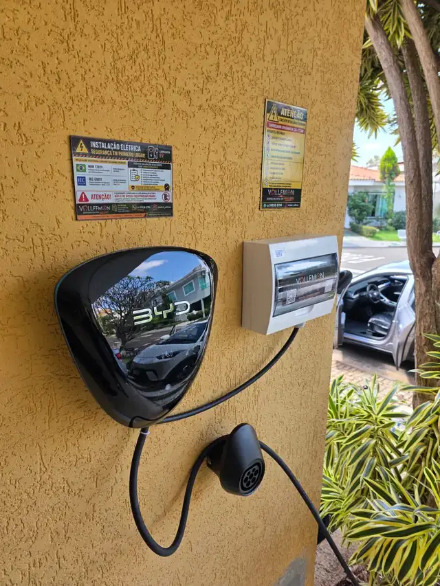 Wallbox BYD e quadro de proteção WEG em casa de condomínio, com carro elétrico ao fundo